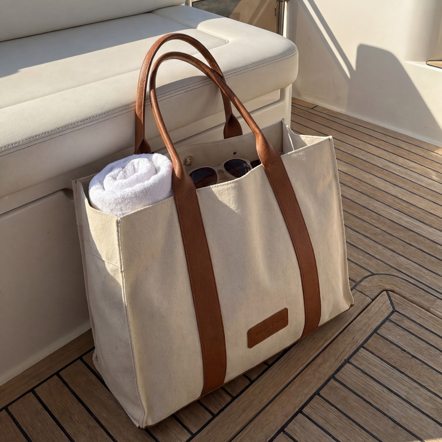 Beige tote bag with brown straps on a boat deck with ocean and cliffs in the background